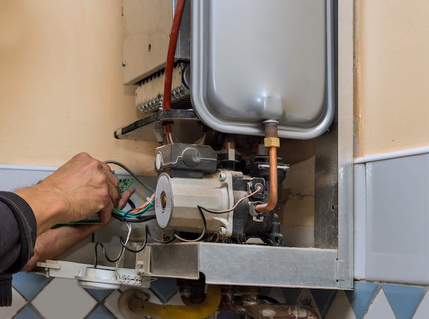 Water heater maintenance service technician repairing gas water heater indoors